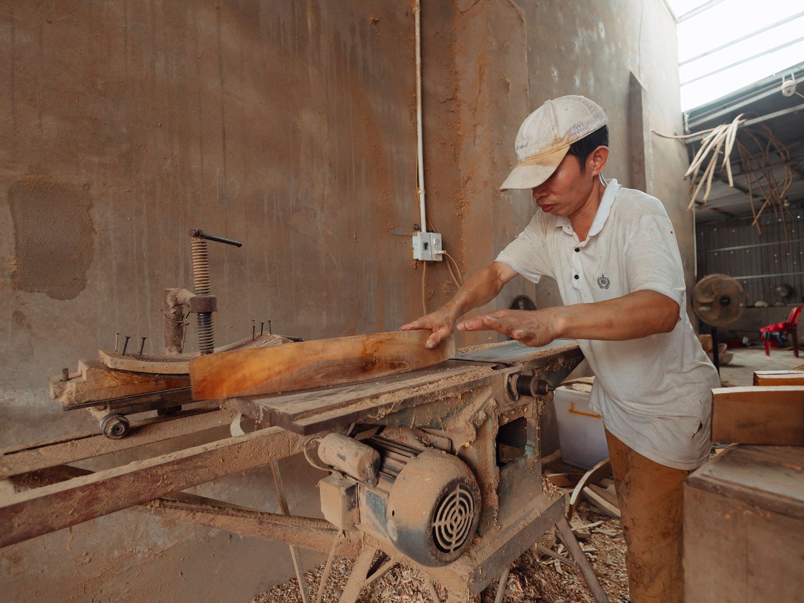 Un menuisier au travail sur une pièce de bois massif dans l'atelier