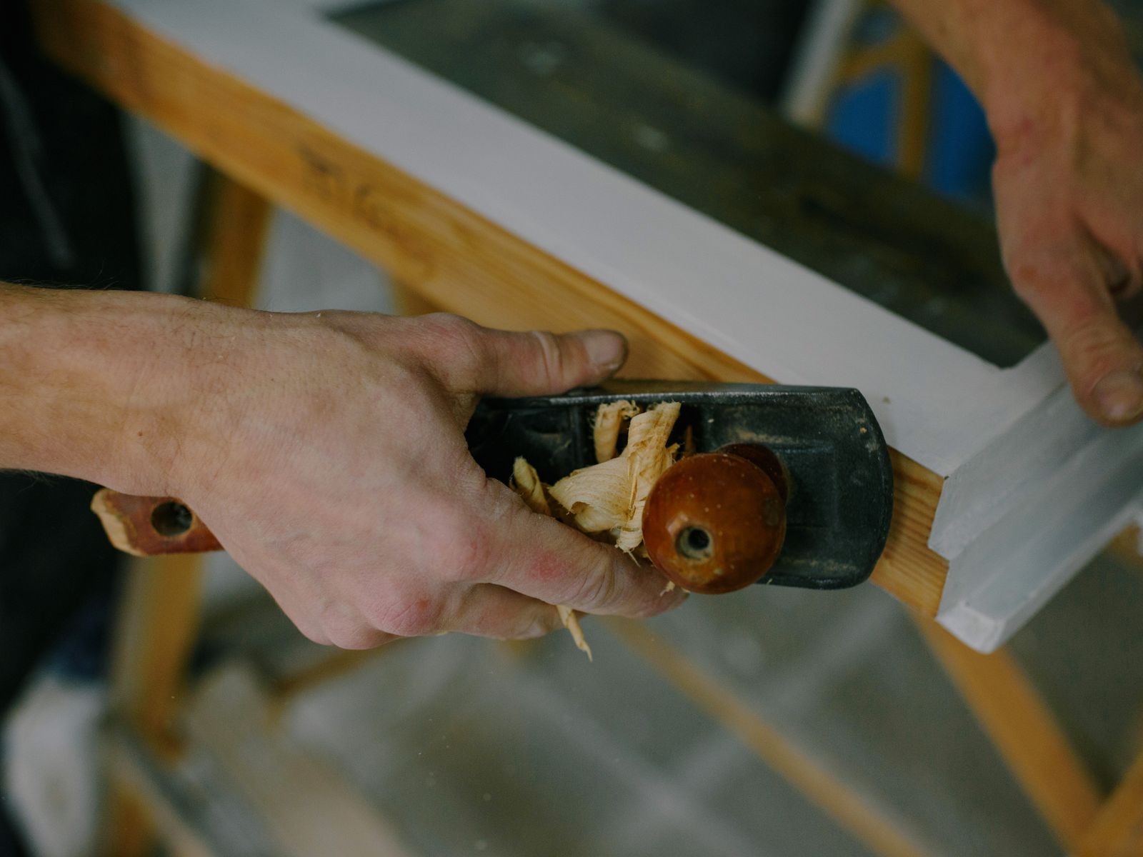 Les mains du menuisier passent le rabot sur une pièce de bois
