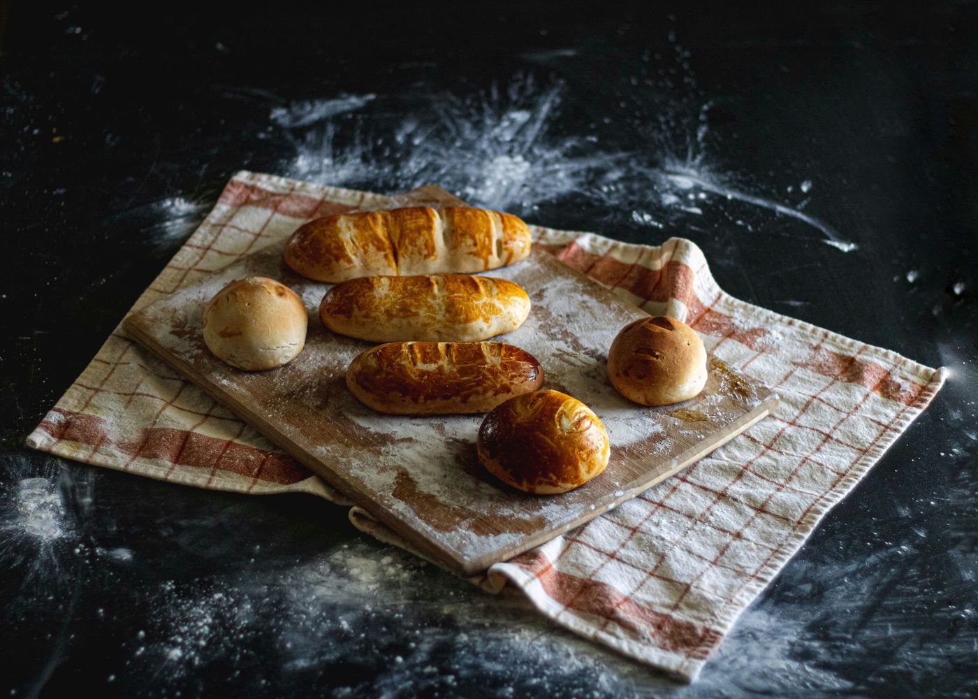Pains dorés saupoudrés de farine sur un linge, à la lueur du fournil
