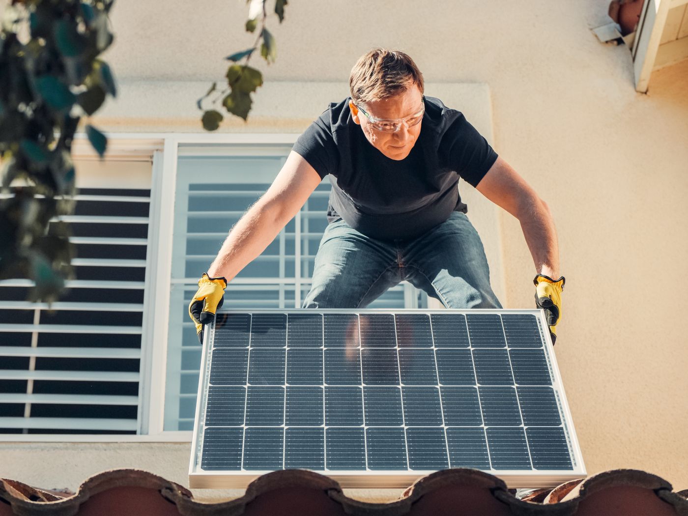 Handwerker montiert ein Solarmodul auf einem Dach