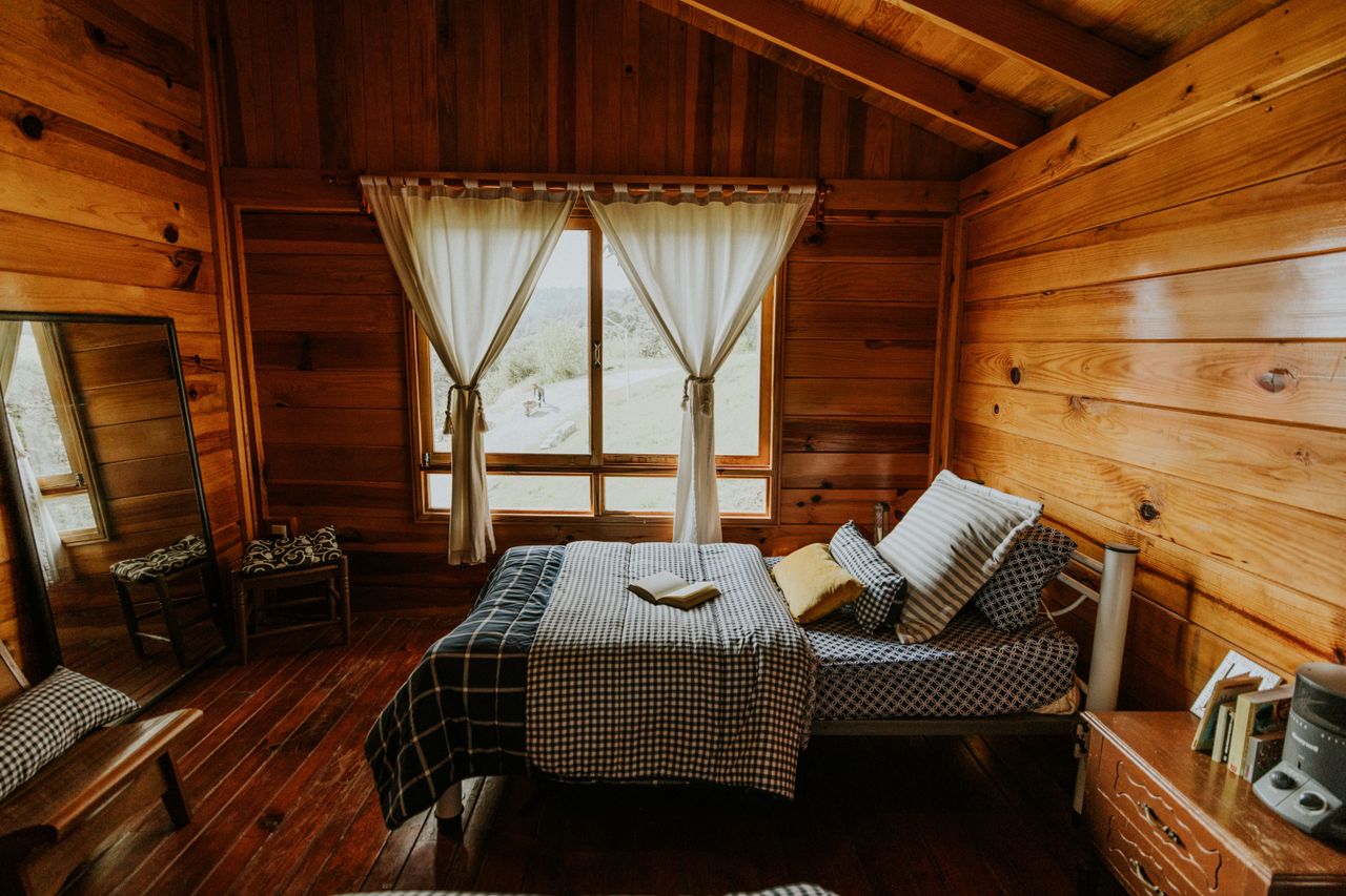 Das Doppelzimmer «Feld» am Morgen, mit Federbett und Blick über die Wiesen