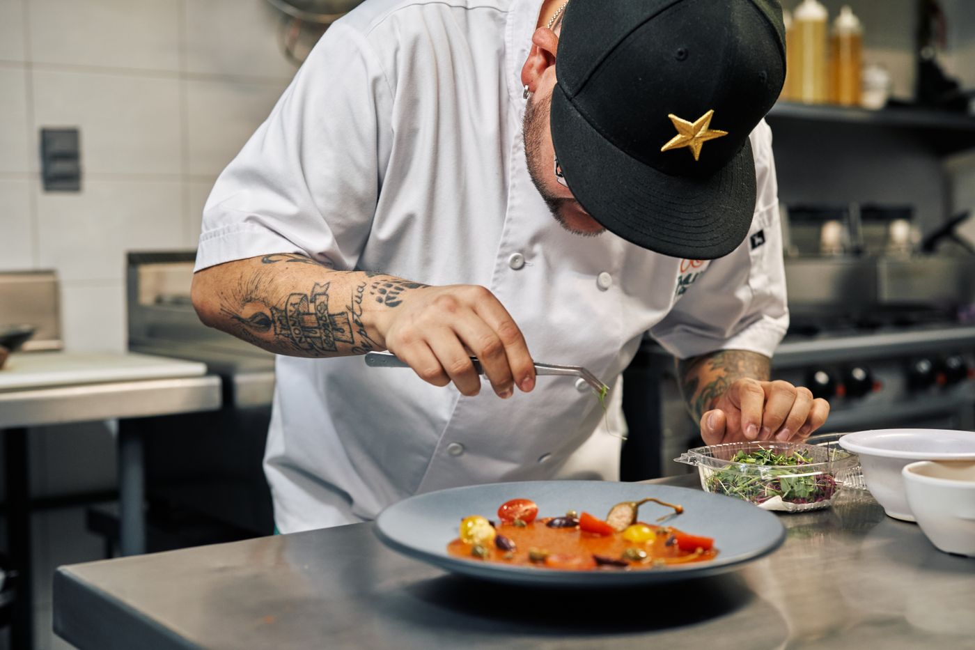 Le chef dresse une assiette à la pince, en cuisine