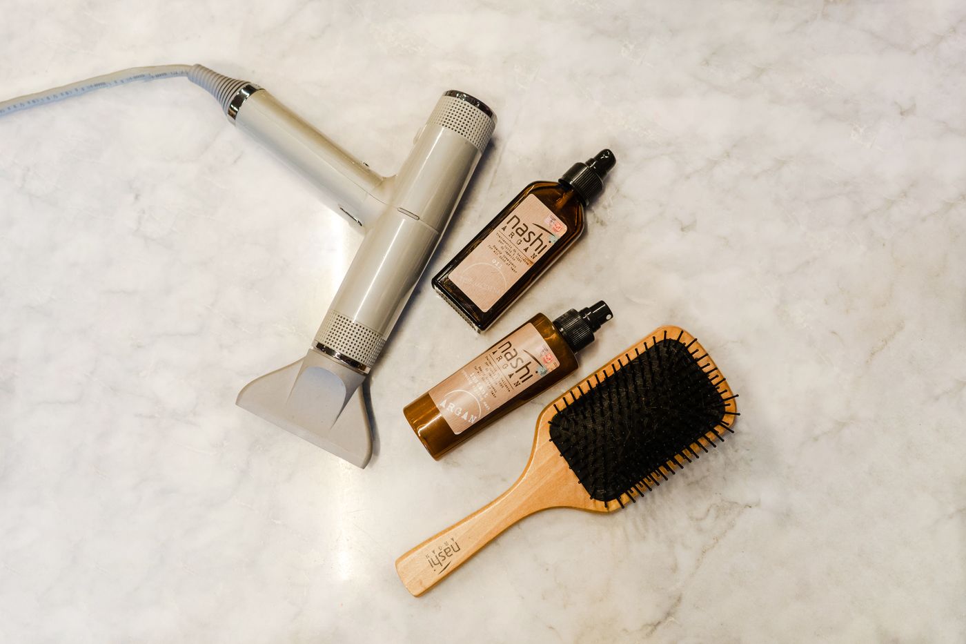 Brosses et soins capillaires disposés sur un plan de marbre